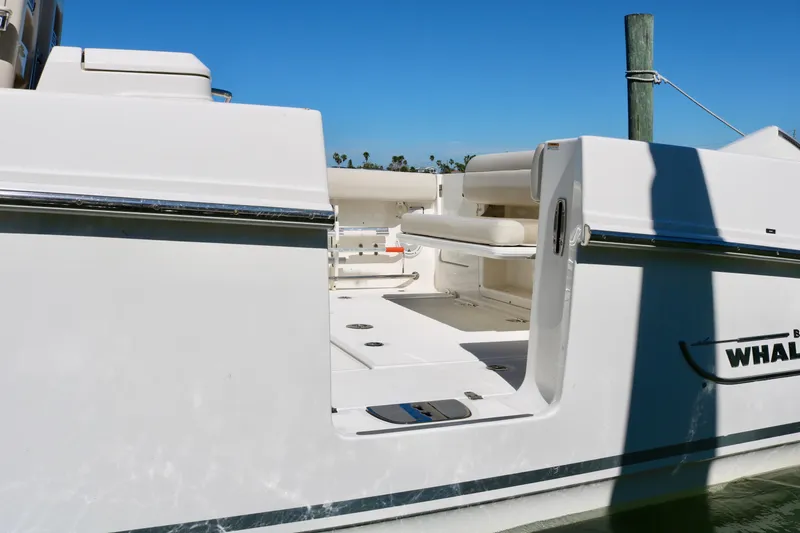 Slide: The Image of 2022 Boston Whaler 330 Outrage boat with open side door, docked under clear blue sky. - 15