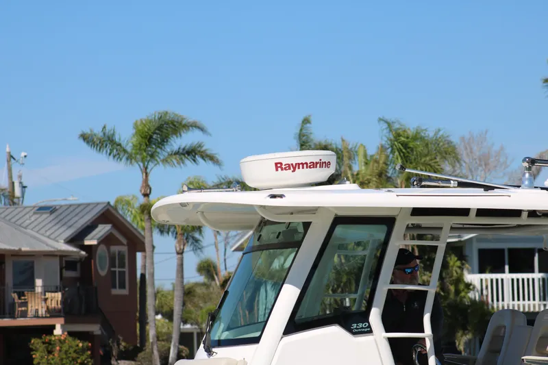 Slide: The Image of 2022 Boston Whaler 330 Outrage boat with Raymarine equipment, docked near palm trees. - 16