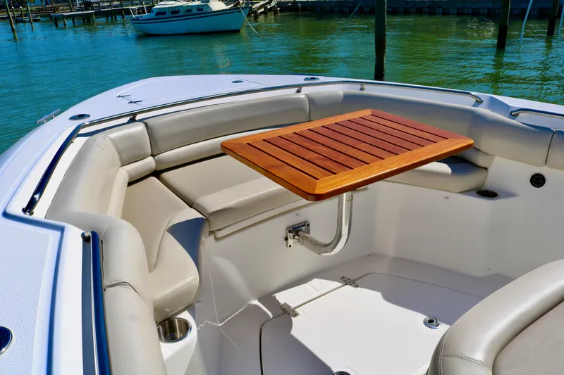 Slide: The Image of 2022 Boston Whaler 330 Outrage boat interior with seating and wooden table. - 17