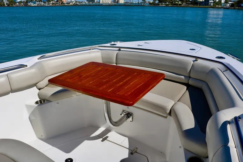 Slide: The Image of Boston Whaler 330 Outrage 2022 boat interior with wooden table and cushioned seating. - 18
