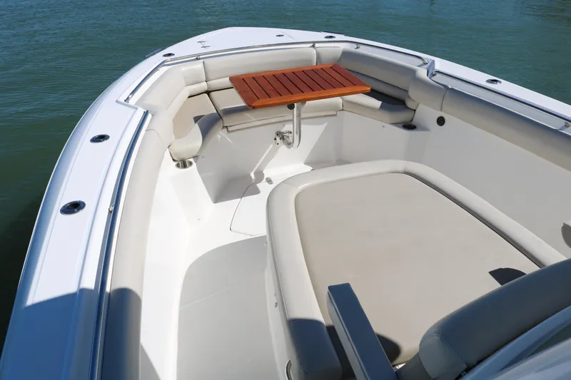 Slide: The Image of 2022 Boston Whaler 330 Outrage boat interior with seating and wooden table. - 19