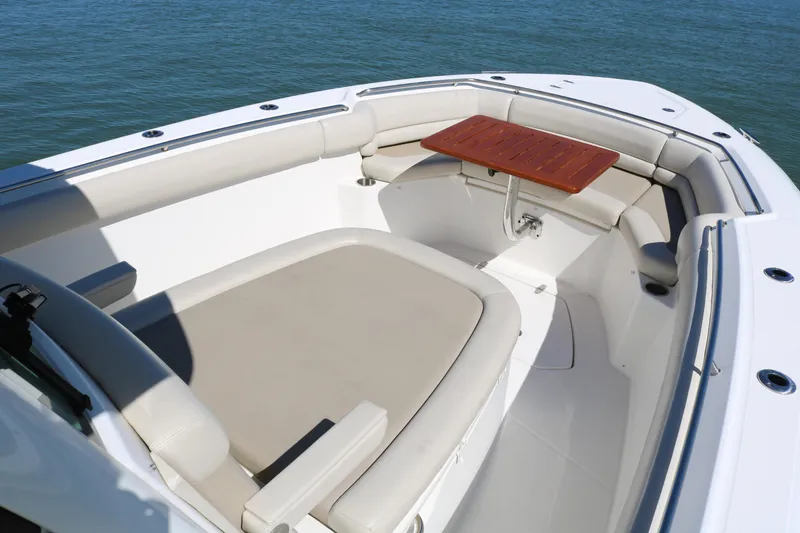 Slide: The Image of 2022 Boston Whaler 330 Outrage boat interior with cushioned seating and wooden table. - 20