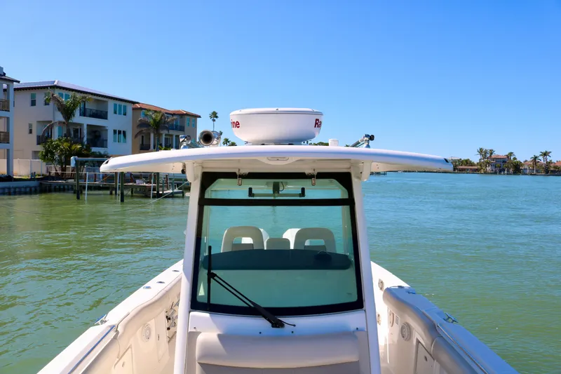 Slide: The Image of Boston Whaler 330 Outrage 2022 on calm water near waterfront homes. - 23