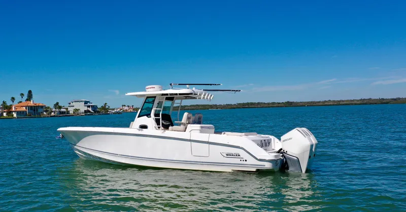 Slide: The Image of 2022 Boston Whaler 330 Outrage boat on calm water under clear blue sky. - 3