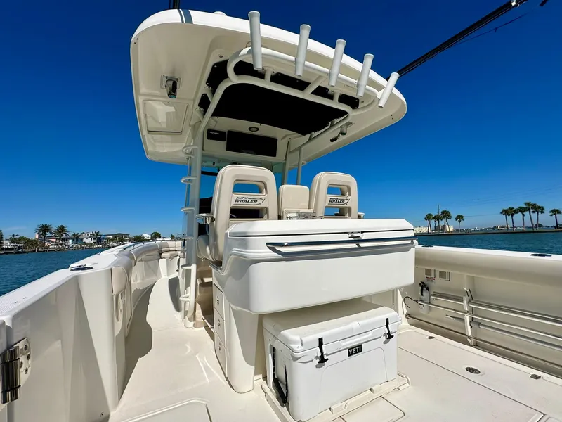 Slide: The Image of 2022 Boston Whaler 330 Outrage boat interior with seating and storage, under clear blue sky. - 30