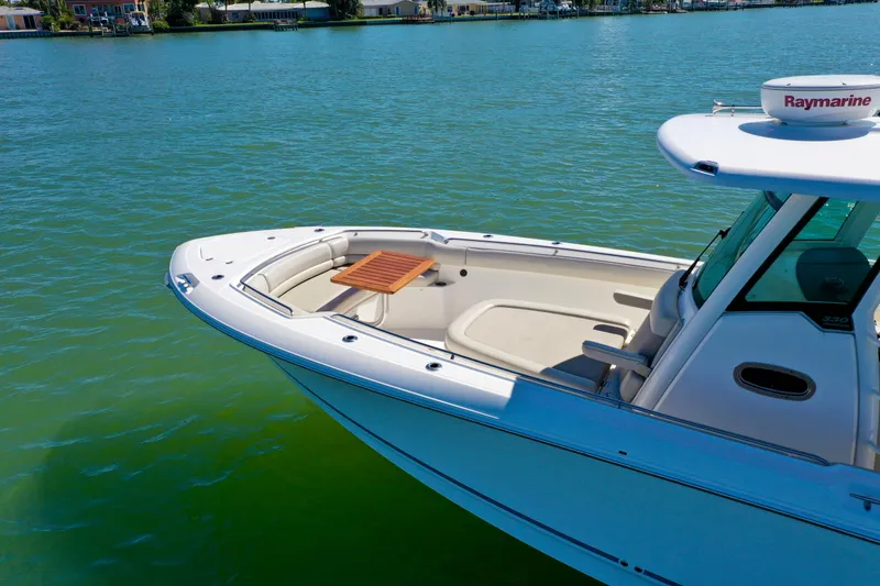 Slide: The Image of Boston Whaler 330 Outrage 2022 on calm water, showcasing sleek design and spacious deck. - 6