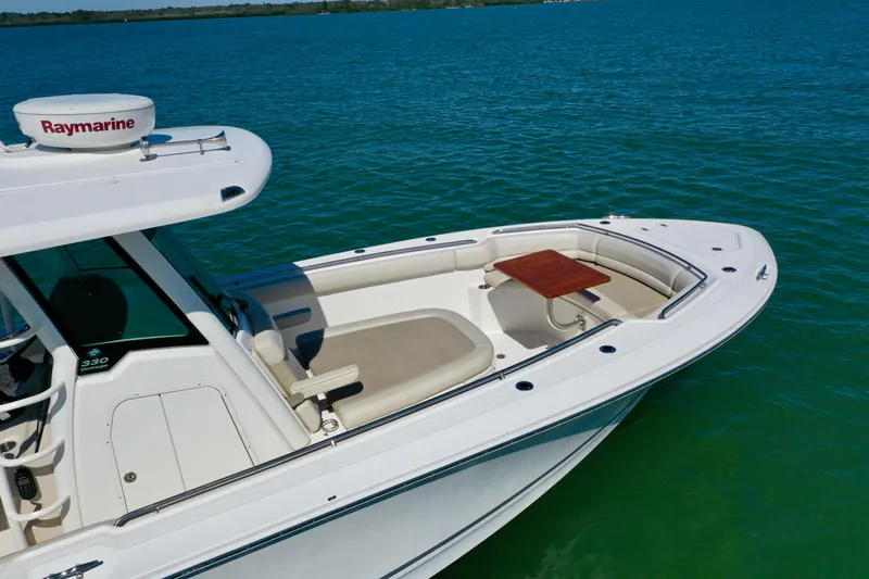 Slide: The Image of 2022 Boston Whaler 330 Outrage boat on water, featuring spacious deck and seating area. - 7