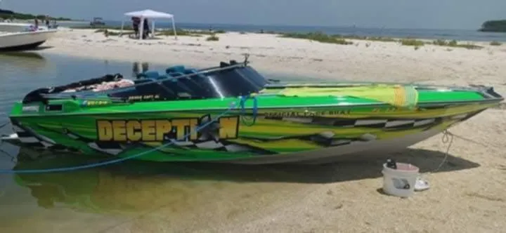 Slide: The Image of 1987 Chaparral Villan II speedboat with vibrant green graphics on a sandy beach. - 10