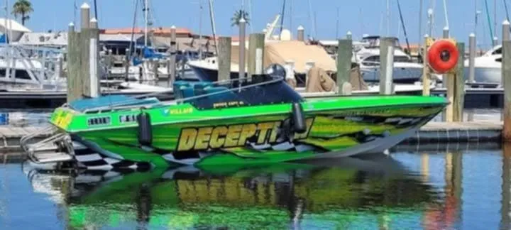 Slide: The Image of 1987 Chaparral Villan II speedboat with vibrant green design docked at marina. - 2