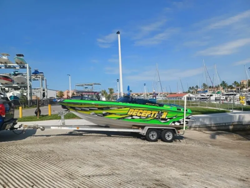Slide: The Image of 1987 Chaparral Villan II boat on trailer at marina, vibrant green design, clear blue sky. - 8