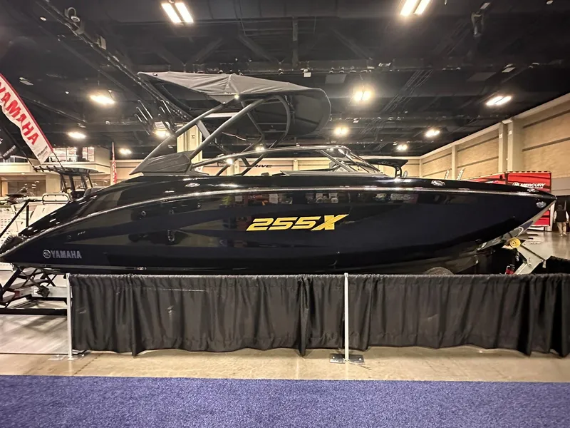 Slide: The Image of 2025 Yamaha Boats 255XD displayed indoors, sleek black design, under bright exhibition lights. - 2