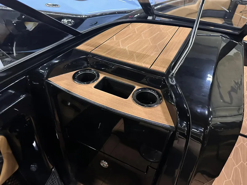 Slide: The Image of 2025 Yamaha Boats 255XD interior with sleek black and wood finish, featuring cup holders. - 31