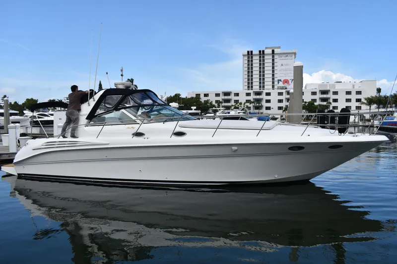 Slide: The Image of 1998 Sea Ray 400 Express Cruiser docked at marina with cityscape background. - 0