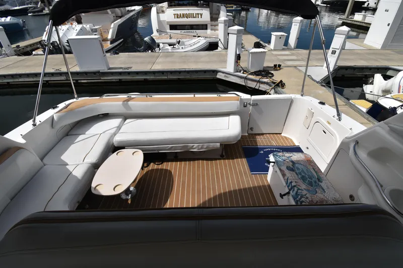 Slide: The Image of 1998 Sea Ray 400 Express Cruiser interior with white seating and wooden flooring at a marina. - 4