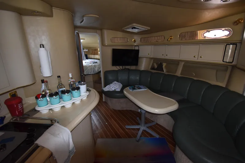 Slide: The Image of 1998 Sea Ray 400 Express Cruiser interior with curved seating, table, and kitchenette. - 5