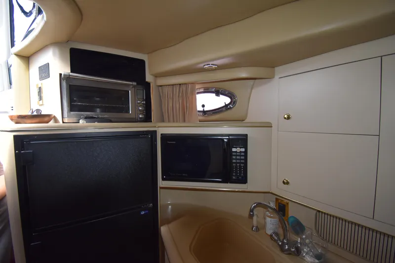 Slide: The Image of 1998 Sea Ray 400 Express Cruiser kitchen with microwave, fridge, and sink. - 7