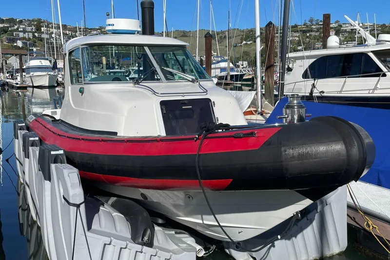 Slide: The Image of 2001 Protector Targa 28 boat docked in a marina, featuring a red and black hull. - 2