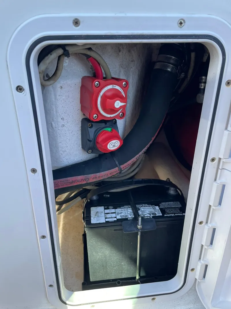 Slide: The Image of Battery compartment of a 2001 Protector Targa 28 boat, featuring wiring and a battery switch. - 24