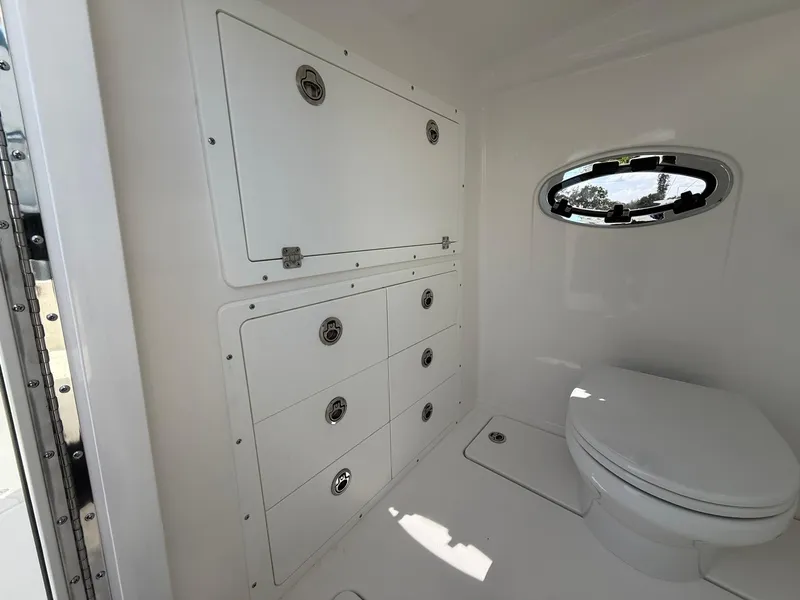 Slide: The Image of 2025 Caymas 34 CT boat interior bathroom with storage cabinets and porthole window. - 20