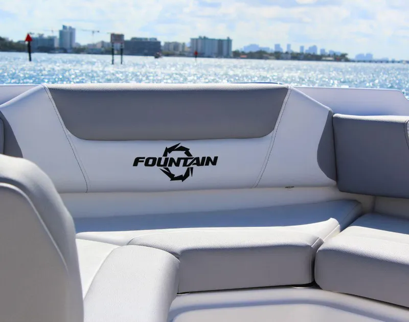 Slide: The Image of 2025 Fountain 32 NX boat interior with logo, overlooking a sunny waterfront. - 14