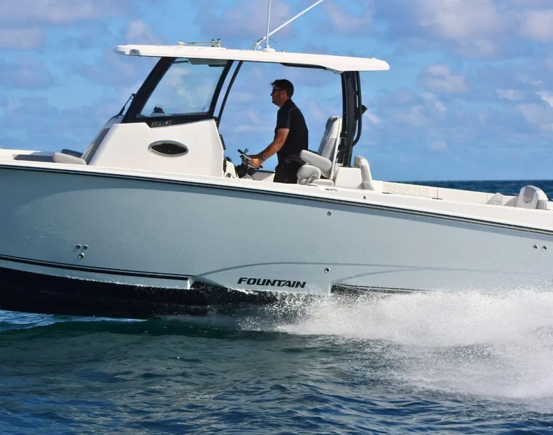 Slide: The Image of 2025 Fountain 32 NX boat cruising on open water under a clear sky. - 2