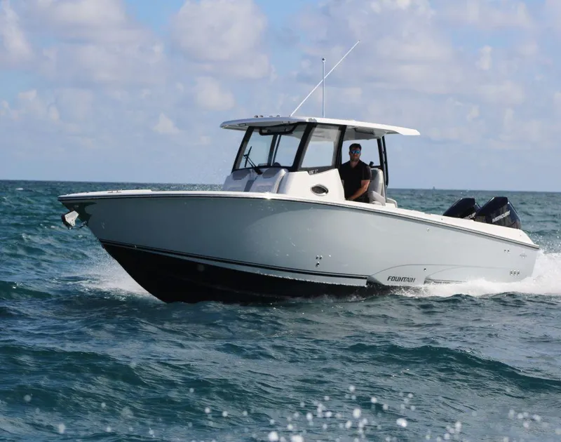 Slide: The Image of 2025 Fountain 32 NX boat cruising on open water under a partly cloudy sky. - 3