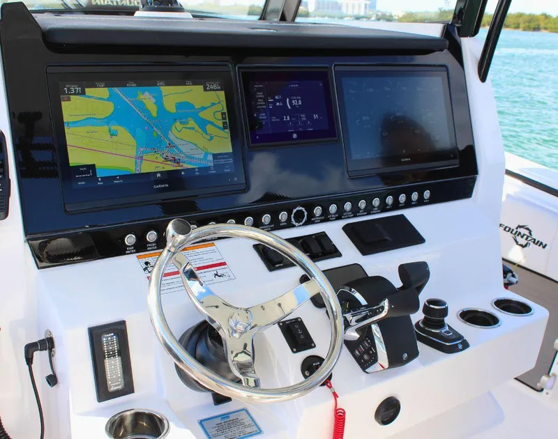 Slide: The Image of 2025 Fountain 38 CC boat dashboard with navigation screens and steering wheel. - 12