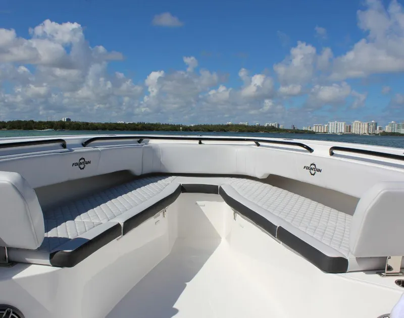 Slide: The Image of 2025 Fountain 38 CC boat interior with cushioned seating under a clear blue sky. - 23