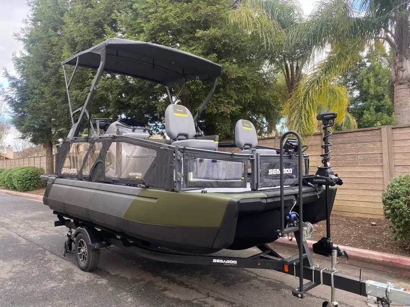 Slide: The Image of 2025 Sea-Doo Switch Fish 18 boat on trailer, parked outdoors with trees in background. - 22