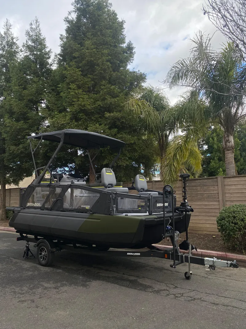 Slide: The Image of 2025 Sea-Doo Switch Fish 18 boat on trailer, parked outdoors with trees in background. - 23