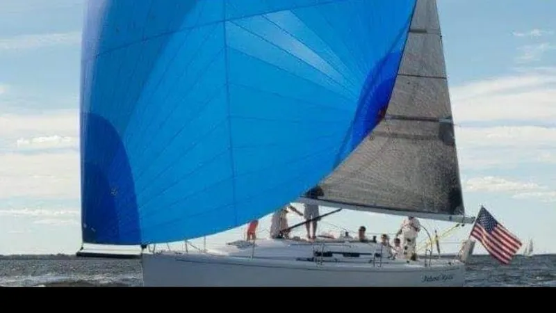 Slide: The Image of 2003 J Boats J/109 sailing with blue spinnaker and American flag on open water. - 3