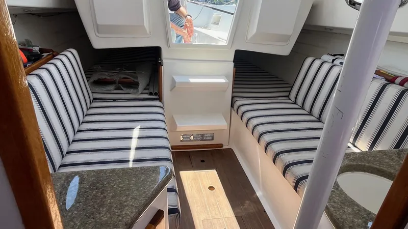 Slide: The Image of 2012 Schock Harbor 25 cabin interior with striped seating and wooden flooring. - 13