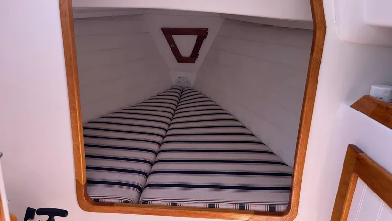 Slide: The Image of 2012 Schock Harbor 25 cabin interior with striped bedding and wooden trim. - 18