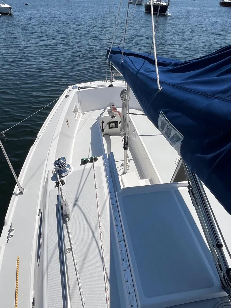 Slide: The Image of 2012 Schock Harbor 25 sailboat with blue cover on calm water. - 6