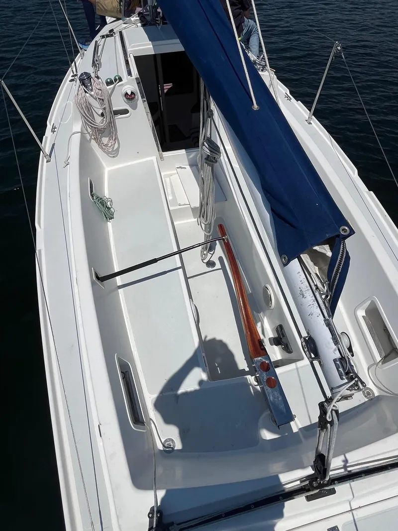 Slide: The Image of 2012 Schock Harbor 25 sailboat deck with blue sail, docked on calm water. - 7