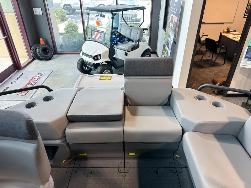Slide: The Image of 2025 Sea-Doo Switch Sport 18 interior with gray seating, cup holders, and a golf cart in the background. - 7