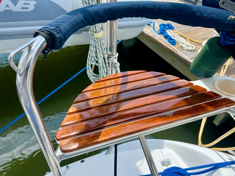Slide: The Image of Polished wooden seat on a 1998 Hunter 410 sailboat, docked with ropes visible. - 13
