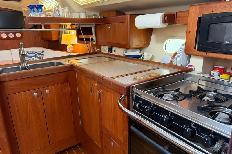 Slide: The Image of 1998 Hunter 410 yacht kitchen with wooden cabinets, stove, and sink. Cozy and well-equipped galley. - 35