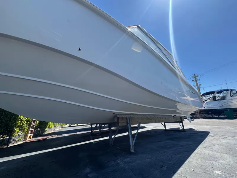 Slide: The Image of 2019 Everglades 340 Dual Console boat on stands, viewed from below, under clear blue sky. - 18