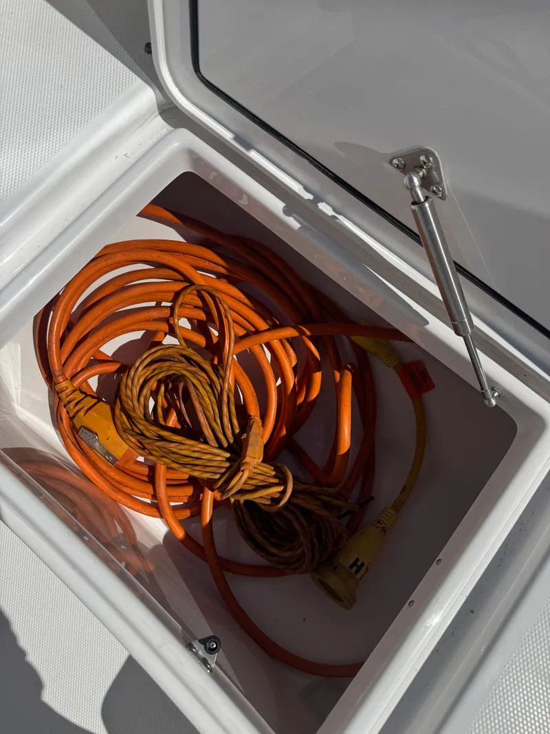 Slide: The Image of Orange extension cord stored in a compartment of a 2019 Everglades 340 Dual Console boat. - 26