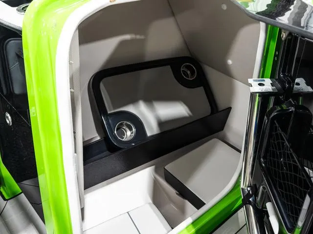 Slide: The Image of 2022 Yamaha Boats 255XD interior storage compartment with green accents and cup holders. - 25