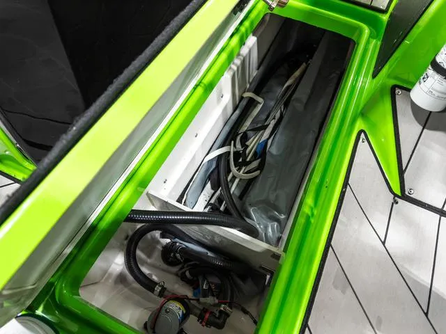 Slide: The Image of 2022 Yamaha Boats 255XD storage compartment with wiring and equipment, featuring vibrant green accents. - 26