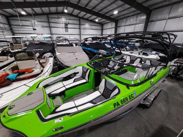 Slide: The Image of 2022 Yamaha Boats 255XD in vibrant green, showcased in a spacious indoor marina. - 4