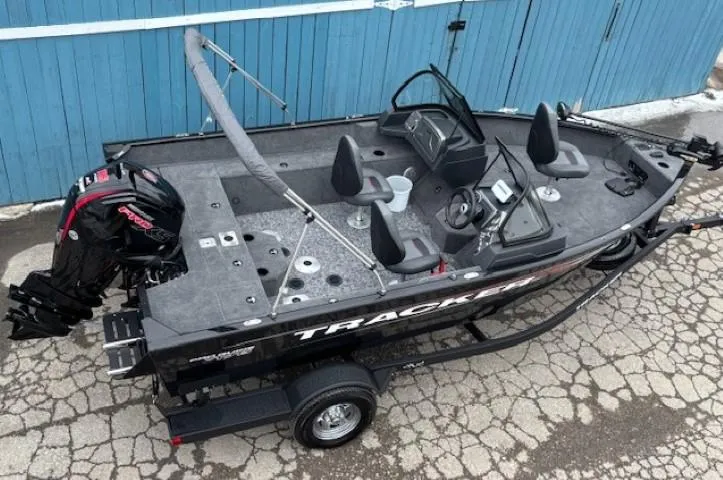 Slide: The Image of 2025 Tracker Pro Guide V-175 WT fishing boat on trailer, parked on cracked pavement. - 5
