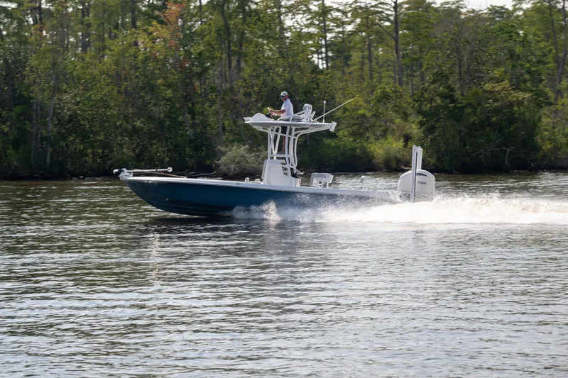 Slide: The Image of 2025 Contender 26 Bay boat cruising on a calm river with lush greenery. - 22