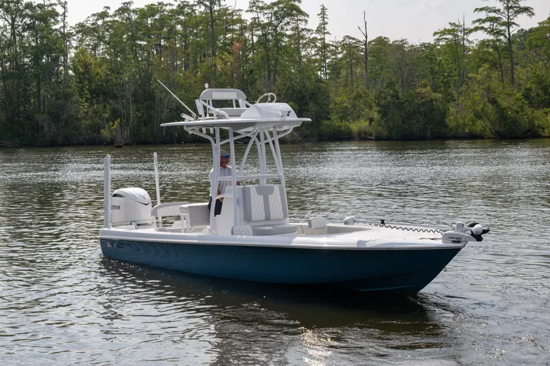 Slide: The Image of 2025 Contender 26 Bay boat on a calm river with lush greenery. - 23