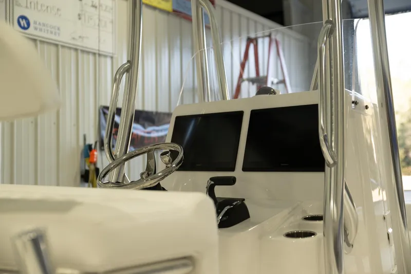 Slide: The Image of 2025 Contender 26 Bay boat interior with dual screens and steering wheel in a workshop. - 4