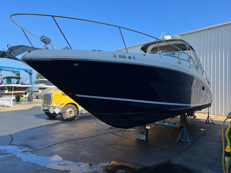 Slide: The Image of 2004 Sea Ray 340 Sundancer boat on dry dock, blue hull, near a yellow truck. - 5