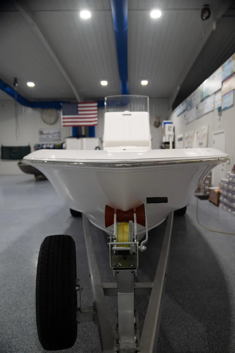 Slide: The Image of 2024 Contender 23 Bay boat on trailer in showroom with American flag. - 3