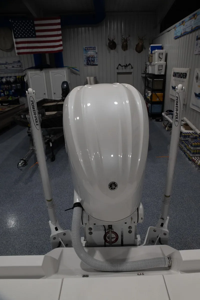 Slide: The Image of 2024 Contender 23 Bay boat engine in a showroom with American flag. - 4